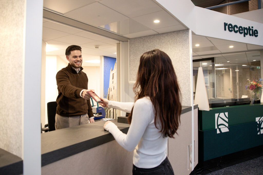 Medewerker Burgerzaken overhandigt een paspoort.
